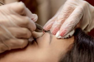 Close-up of a beautician hands applying japanese method of drawing on eyebrows to model.